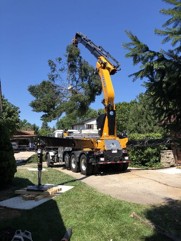 Boom lift vehicle in action moving a large section of a tree.